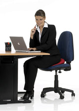 Frau in Businesskleidung sitzt auf einem Bürostuhl, arbeitet an einem Laptop und telefoniert.