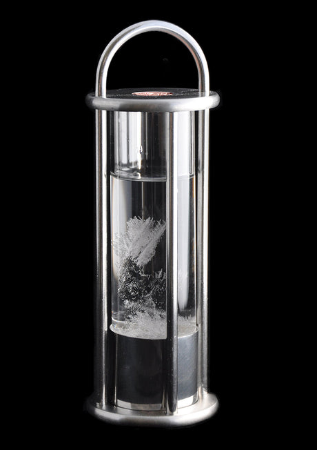 Vakuum-Kristalle im Wasser, eingeschlossen in einem Glasbehälter mit Metallrahmen.