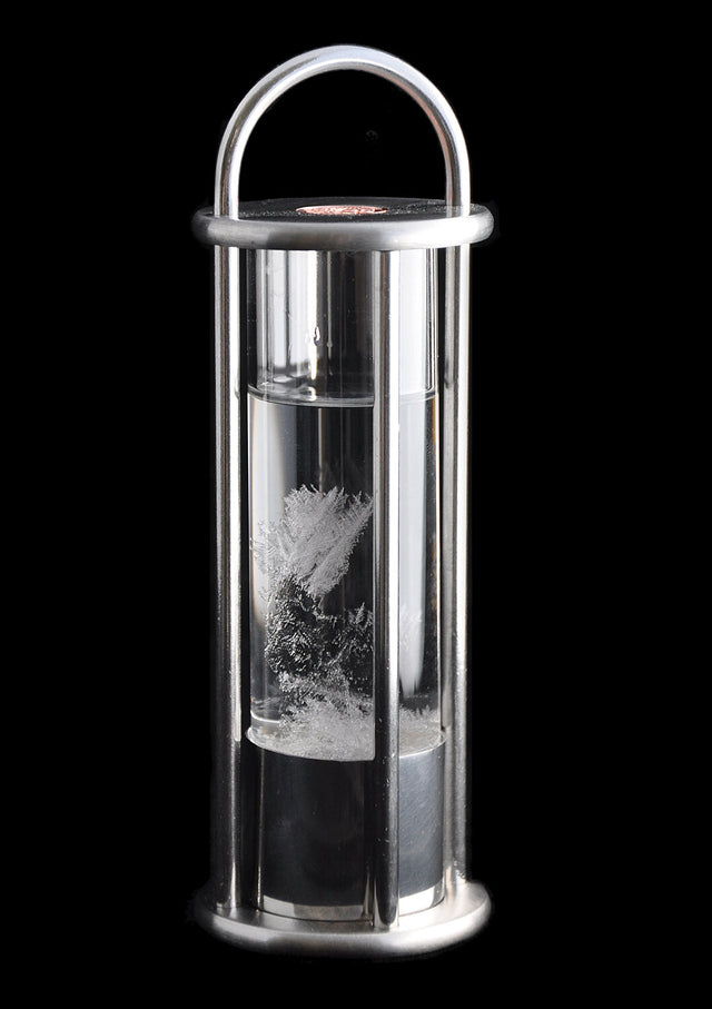 Vakuum-Kristalle im Wasser, eingeschlossen in einem Glasbehälter mit Metallrahmen.