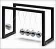 Newtonpendel mit fünf metallischen Kugeln, die an Schnüren zwischen zwei schwarzen Rahmen hängen.