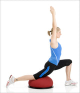 Frau in Sportkleidung macht Yoga-Übung auf Balance- und Fitnessball, mit einem Arm nach oben gestreckt.