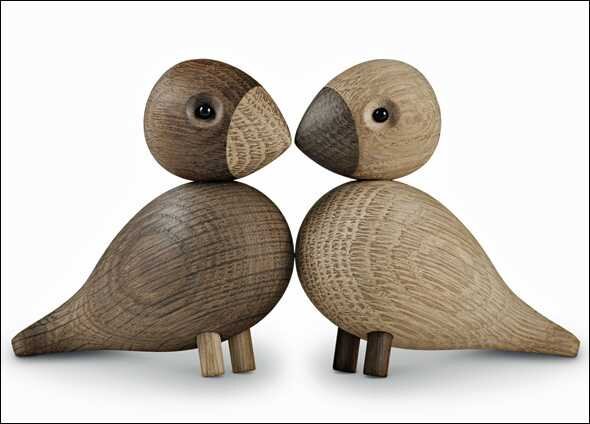 Zwei Holzvögel mit runden Köpfen, großen Augen und kurzen Beinen, die sich berühren.