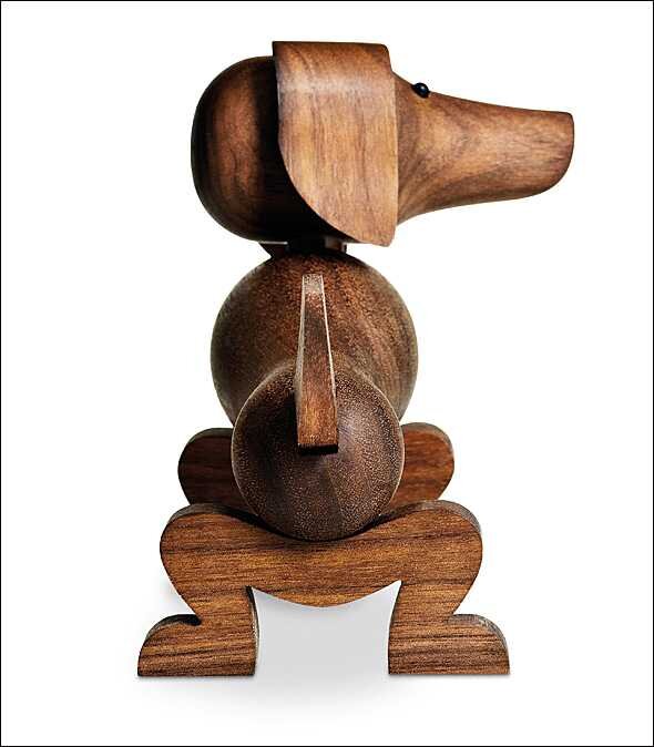 Holzfigur eines sitzenden Hundes mit langen Ohren, Nase und Schwanz, aus verschiedenen Holzstücken gefertigt.