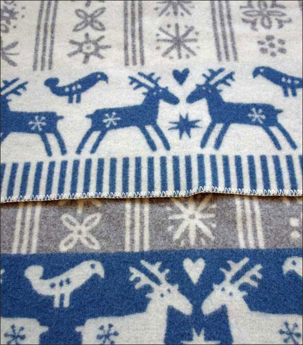 Stoff mit blauen Rentieren, Schneeflocken und Herzmotiven auf weißem Hintergrund.