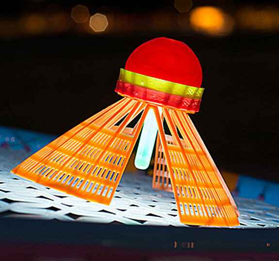 Leuchtendes Spielzeug in Form eines UFOs mit roten, gelben und blauen Elementen auf einer weißen Oberfläche bei Nacht.