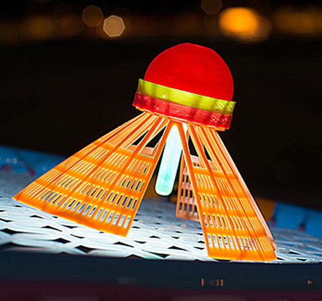 Leuchtendes Spielzeug in Form eines UFOs mit roten, gelben und blauen Elementen auf einer weißen Oberfläche bei Nacht.