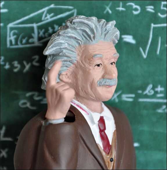 Statue von Albert Einstein mit Finger an Kopf, vor einer Tafel mit mathematischen Formeln.
