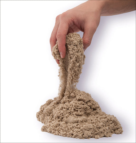 Hand hält feuchten Sand, der nach unten rieselt, auf weißem Hintergrund.
