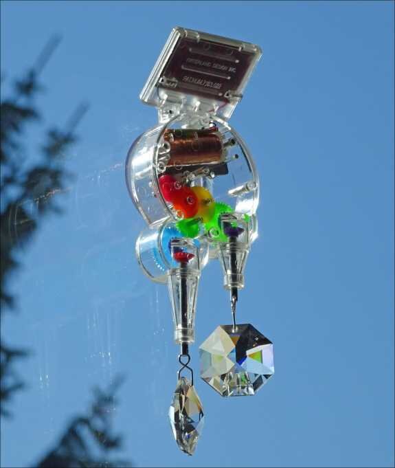 Hochsicht auf eine Solar- oder Windenergieanlage mit bunten Kugeln und Kristallen, gegen blauen Himmel.