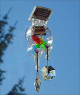 Hochsicht auf eine Solar- oder Windenergieanlage mit bunten Kugeln und Kristallen, gegen blauen Himmel.