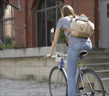 Frau fährt mit Fahrrad an einer Treppe vorbei, trägt einen Rucksack und ein graues T-Shirt.