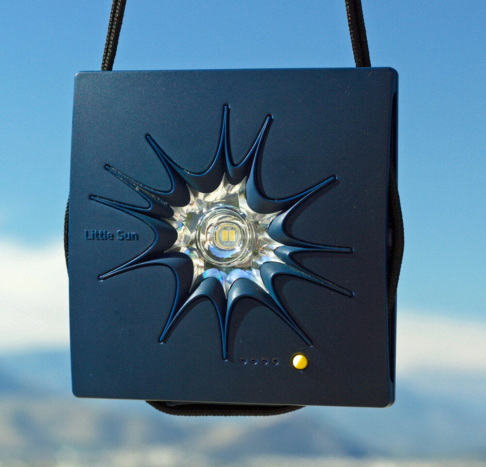 Kleiner, blauer Sonnen- oder Lichtprojektor mit schwarzem Band, auf blauem Himmel.