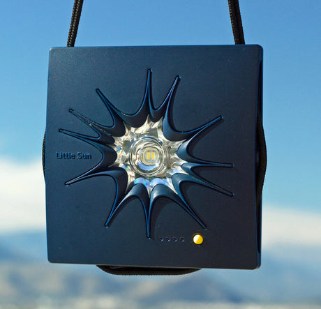 Kleiner, blauer Sonnen- oder Lichtprojektor mit schwarzem Band, auf blauem Himmel.