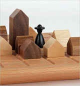 Schachfigur auf einem Holz-Schachbrett mit Holzhäusern als Figuren.