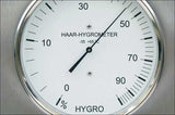 Haar-Hygrometer mit Zeiger bei etwa 15 %, zeigt Luftfeuchtigkeit an.
