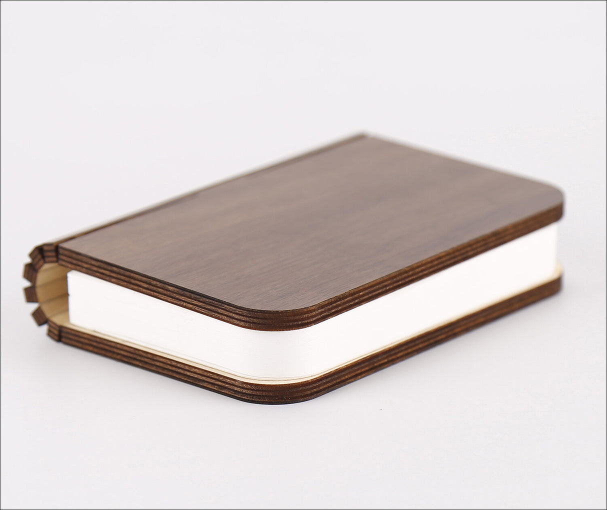 Ein Buch mit braudem Holzdeckel und weißen Seiten, liegt auf weißem Hintergrund.
