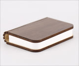 Ein Buch mit braudem Holzdeckel und weißen Seiten, liegt auf weißem Hintergrund.