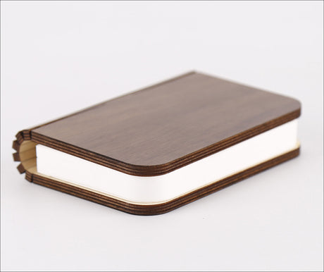 Ein Buch mit braudem Holzdeckel und weißen Seiten, liegt auf weißem Hintergrund.