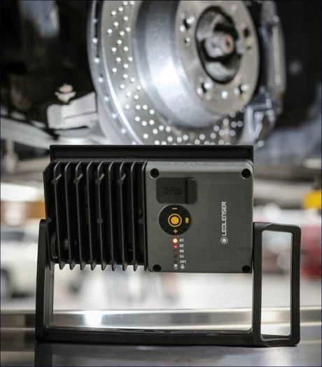 Gerät mit Kühlrippen vor einer großen, perforierten Metallplatte, vermutlich in einer Werkstatt.