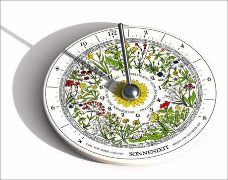 Kombination aus Uhr und botanischem Kalender mit bunten Blumenmotiven, Sonnenzeichen und Zeiger.