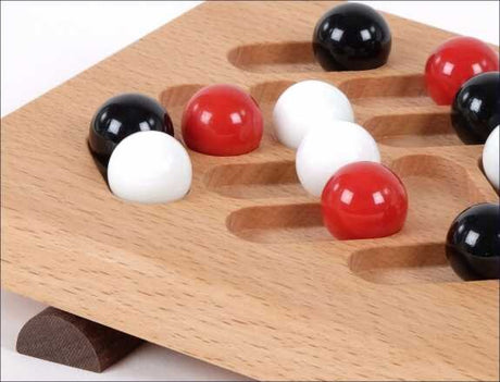Holzspielbrett mit roten, weißen und schwarzen Kugeln in Vertiefungen.