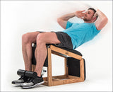 Mann liegt auf einem Pilates-Reformer, entspannt mit Händen hinter dem Kopf, trägt ein blaues T-Shirt und schwarze Shorts.