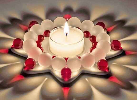 Teelicht in der Mitte, umgeben von weißen und roten Kugeln, auf einer mehrschichtigen, blumenförmigen Anordnung.