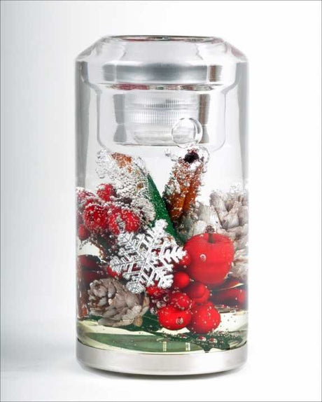 Glas mit Wasser, gefüllt mit Weihnachtsdekorationen wie Beeren, Schneeflocken, Tannenzapfen und Zimtstangen.