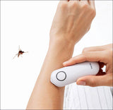 Hand hält elektrischen Insektenvernichter an Unterarm, Insekt fliegt in Richtung Gerät.