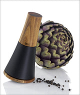 Elektrischer Pfeffermühle mit Holz- und schwarzen Kunststoffteilen, Artischocke und Pfefferkörner im Hintergrund.