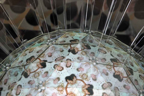 Ein aufgespanntes transparentes Regenschirm mit einem Muster aus mehreren Frauen.