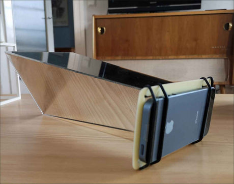 Smartphone in Halter, auf einem Holztablett, mit Spiegel im Hintergrund.