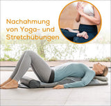 Frau liegt auf einer Yogamatte in Rückenlage, mit Kissen unter dem Kopf, im Wohnzimmer.