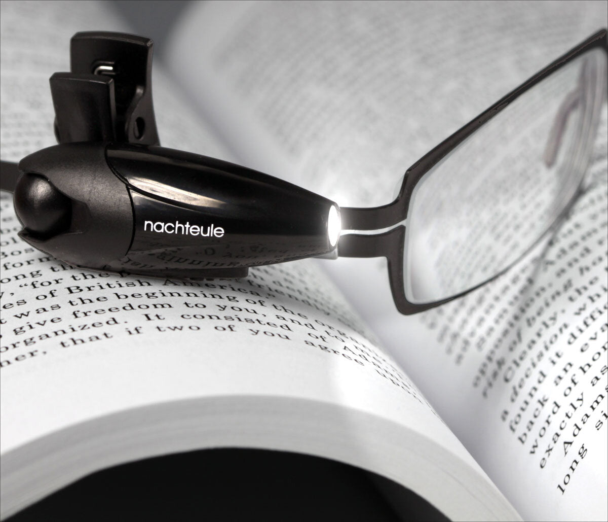 Brille mit integriertem Licht auf einem offenen Buch mit Text.