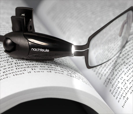 Brille mit integriertem Licht auf einem offenen Buch mit Text.