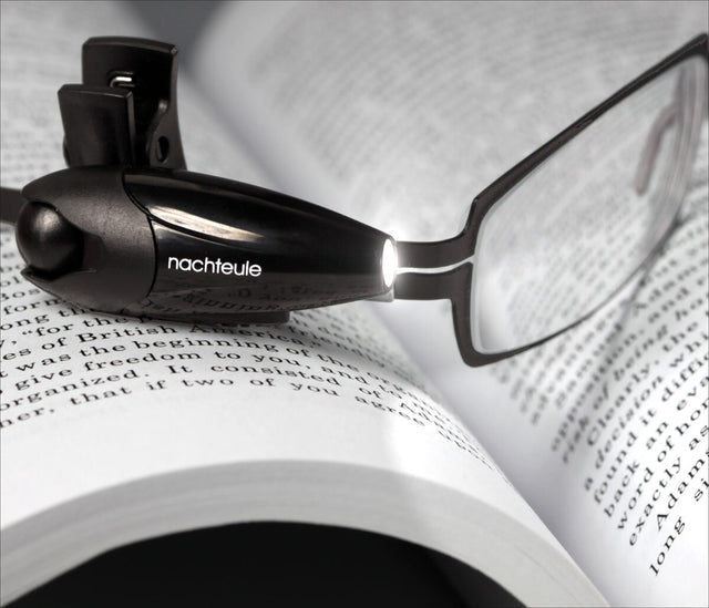 Brille mit integriertem Licht auf einem offenen Buch mit Text.