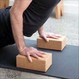 Person in Yoga-Position auf Händen und Füßen, Hände auf Yoga-Blöcken, im Raum.