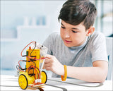 Junge baut einen kleinen Roboter mit gelben Rädern, Kabeln und elektronischen Komponenten.