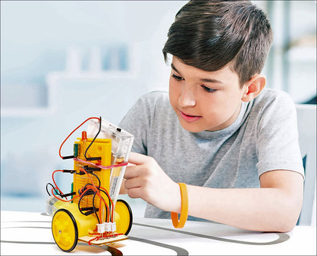 Junge baut einen kleinen Roboter mit gelben Rädern, Kabeln und elektronischen Komponenten.