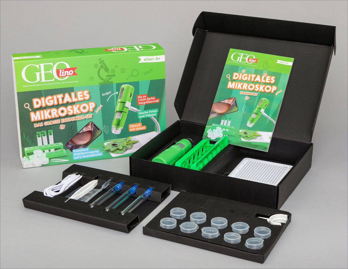 Offene Box mit Mikroskop-Set, Anleitung, Zubehör und Verpackung, alles in Schwarz und Grün.