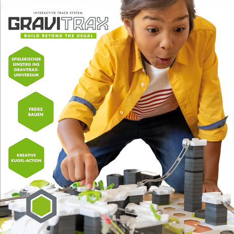 Junge Person spielt mit einem interaktiven Gravitrax-Kugelbahn, die auf einem weißen Untergrund aufgebaut ist.