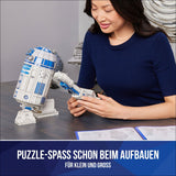 Frau baut LEGO R2-D2 Modell, Anleitung liegt auf Tisch, Text: "Puzzle-Spass schon beim Aufbauen für klein und groß".
