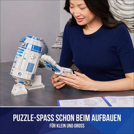 Frau baut LEGO R2-D2 Modell, Anleitung liegt auf Tisch, Text: "Puzzle-Spass schon beim Aufbauen für klein und groß".