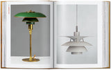 Zwei Designer-Lampen, eine grüne mit goldfarbenem Standfuß, die andere weiße mit mehreren Schichten, hängen an einer Buchseite.