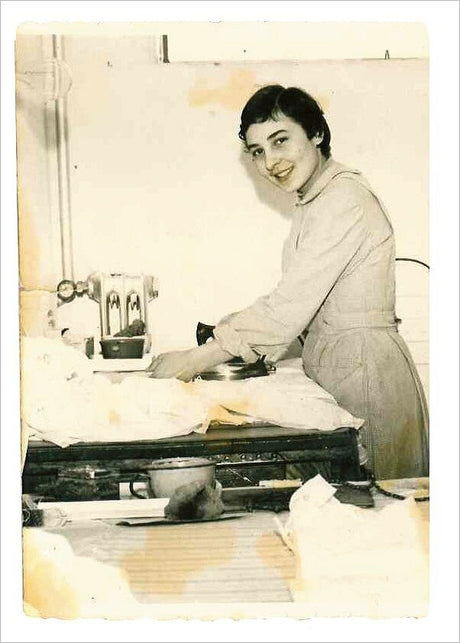 Junge Frau in Küchenumgebung, lächelnd, beim Kochen oder Arbeiten am Herd.