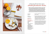 Bodenständiger, mit Puderzucker bestäubter Florentiner-Kuchen mit Orangenscheibe und Zitrone, auf Teller und Küchenutensilien.