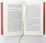 Offen gebundene Buch mit grünem Lesezeichen, sichtbarer Text auf beiden Seiten.