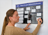 Frau schreibt auf ein schwarzes Plakat mit Karte und Textfeldern, das "Tatort Escape Adventskalender" heißt.