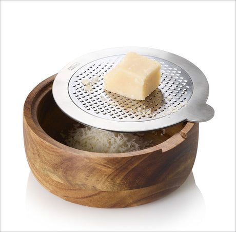 Block Hartkäse auf einer Metallreibe über einem Holzschüssel mit geriebenem Käse.