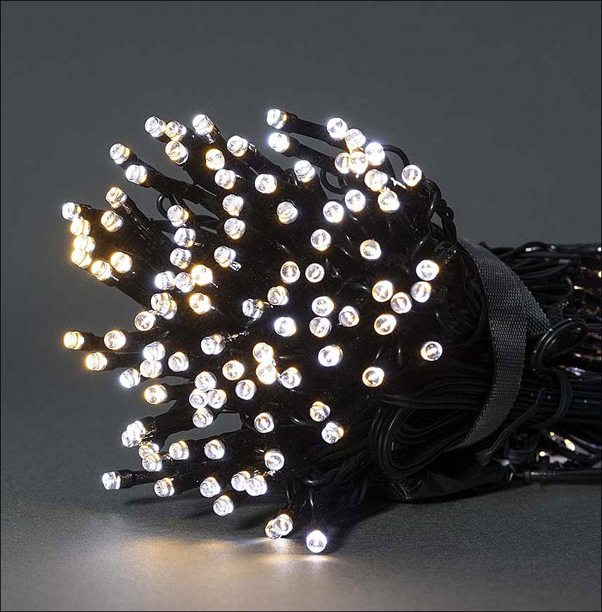Lichterkette mit vielen kleinen, leuchtenden LEDs, aufgerollt und auf dunklem Hintergrund.